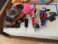 Purses, wallets, padded hangers, pink hat, and gloves arranged on a bed.