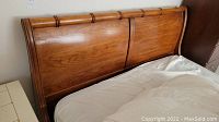 Close-up of polished wooden headboard showing curved design and wood grain.