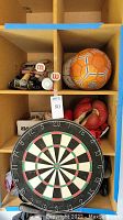 Dartboard, various balls, boxing gloves in cubby shelves