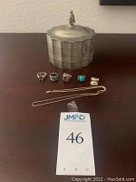 Lot displaying 4 rings with various stones, sterling silver chain, pendant, and pewter jewelry box.