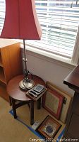 Photo showing adjustable height lamp on the Stickley mission-style round side table along with picture frames below and nearby on the floor
