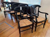 Six wood chairs, two with armrests and four without, all with woven blonde rattan seats and dark stained wood frames