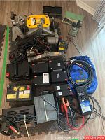 Overview of battery chargers, modules, cables and diagnostic tools arranged on floor