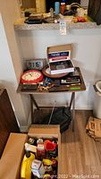 Top view of small table holding clocks, calculator, small keys, and boxes with various items.