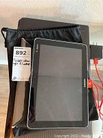 Samsung Galaxy tablet with T-Mobile branding on black soft carrying pouch, charger cable visible
