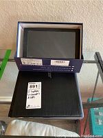 Two closed laptops, one black and one silver, with a GPS navigation box on top