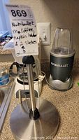 Photo showing NutriBullet blender base and paper towel holder on a kitchen countertop, along with the Mr. Coffee machine in the background.