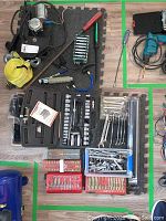 Various assembled socket wrench sets, wrenches, ratchets, screwdriver bits, and other hand tools arranged on foam mat and floor.