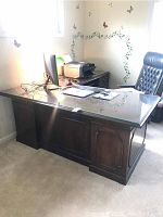 Full view of main L-shaped desk piece showing dark wood and glass surface with office items on top.