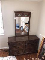 Full view of dresser with mirror showing carved wood detailing and rectangular mirror above dresser.