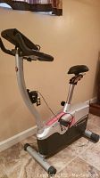Side view of Schwinn exercise bike showing silver frame, black seat and base with digital console on handlebars.