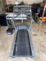 Front view of Life Fitness treadmill showing handrails, control panel, and running belt within garage space.