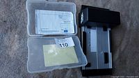 Manual credit card machine and plastic case with carbon sheets on a surface.