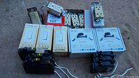 Photo of all electrical items including dimmer switches, outlets, and circuit breakers arranged on the ground.