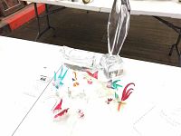 Clear crystal ashtray and assorted colorful hand blown glass animal figures including swans, fish, pelicans, and roosters displayed on a table.