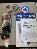 Overview of all items laid out on table showing Tascam box, manual, and guitar parts and accessories