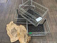Three metal wire crates stacked with two Courtyard branded burlap sacks on a wooden floor.