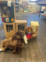 Lot showing all plush items on wooden floor including Dinosaur and bear boxes.