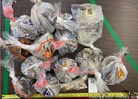 Photo shows 14 plastic bags filled with rocks, minerals, and pebbles arranged on a surface.