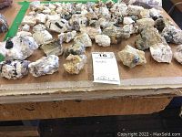 Photo showing a variety of over 50 rocks and mineral stones laid out on a table, primarily white stones with black inclusions.
