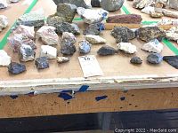 Top view of a table filled with over 20 various natural rocks showing different sizes, shapes, and colors including light and dark hues.