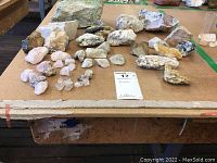 Overview photo showing over 25 assorted rough rocks and minerals placed on a tabletop.
