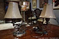 Pair of brass phoenix lamps on wooden table in room setting