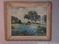 Full view of framed landscape artwork showing a field of bluebonnet flowers and a large tree under a partly cloudy sky.