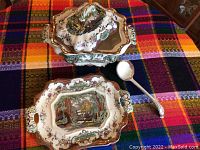 Top view of terrine with lid, matching platter, and ladle on colorful textile surface