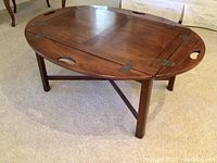 Round mahogany table with sides unfolded on beige carpet, showing full table surface and leg structure.
