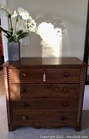 Front view of dresser showing four drawers, turned spiral front side columns, wooden knobs, key in top drawer, top surface with decorative plant