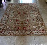 Full view of the large wool rug showing the overall floral and ornamental pattern with dominant red, yellow, beige, and greenish hues.