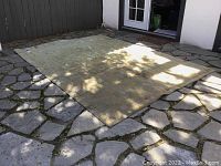 Full view of the large mustard yellow and blue geometric rug laid out on stone floor.