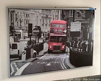 Frontal photo of the art print showing red double decker bus in black and white cityscape with the bus highlighted in red.