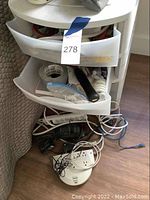 Side view of the white plastic three-drawer storage unit filled with hardware, tape, and tools.