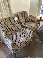Pair of black and white patterned chairs side by side near a curtain.