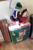 Photo of a decorative rocking horse figurine with a mounted figure dressed in blue and green standing on top of a box containing the Victorian village set.