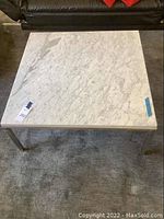 Full top view of the square coffee table showing the white marble or granite top with natural veining.