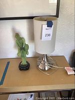 Photo showing the lamp and the green plastic statue side by side on a brown surface.