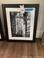 Framed black and white photo of NYC street signs including Union Square West and East 16, mounted in a black frame with white matting and visible blue tape showing measurement.