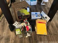 Photo showing all office supplies laid out including notebooks, basket, pens, markers, stapler, and golf balls
