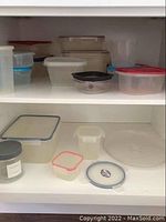 Shelf with multiple plastic food storage containers in various sizes and lids