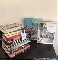 Stack of various coffee table books including Codename Cartoon and Sense of Place, with one Los Angeles architecture book propped behind