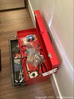 Top view of open red metal Husky toolbox filled with assorted hand tools and accessories, showing general contents and layout.