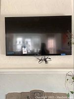 Full view of Toshiba 49" flat screen TV mounted on wall with power cord tied underneath.