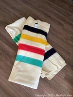 Two folded wool blankets, one striped and one solid cream