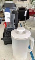 Vitamix blender base with blending container and white mixing pitcher on countertop