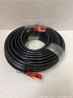 Coiled black Ethernet cable with visible red RJ45 connectors on each end and protective wrapping around the cable center.