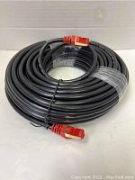 Full coiled view of the black 20M Ethernet cable showing the entire length coiled with red RJ45 connectors at the ends.