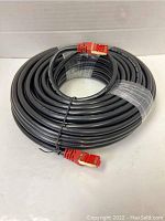 Full view of coiled black Ethernet cable with red RJ45 connectors on each end, secured with black and clear plastic ties.